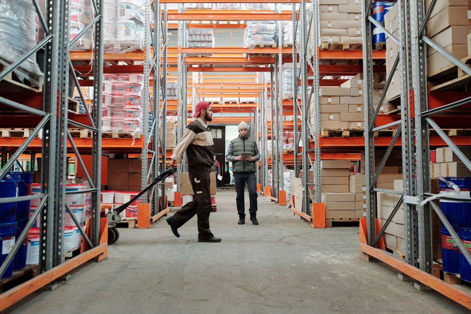 Warehouse aisle with pallet racks and staff